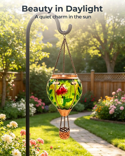 Glass Hot Air Balloon Solar Lantern With Flame Hand Painted Artwork Realistic Flickering Flame Hummingbird Accent Rustproof Metal Outdoor Solar Light For Garden Or Yard Easy Setup And Eco Friendly hanging in garden with flowers.