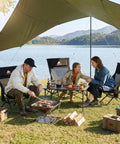Family enjoying picnic with Armless Rocking Camping Chair With Spring Action Tech, Heavy Duty Mesh Seat, by lakeside campsite, under canopy.