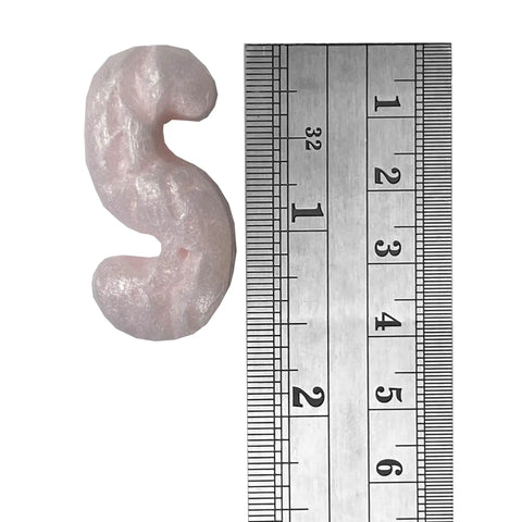 Pink packing peanuts for shipping and moving, showing a piece beside a ruler for size comparison.