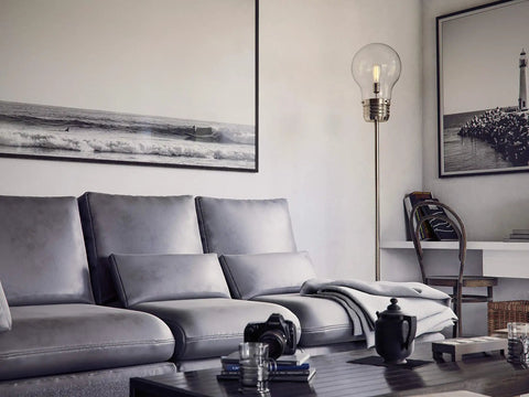 Edison Floor Lamp In Antique Brass Finish, Clear Glass Shade, Rustic Vibe, 71.5 Inch Tall illuminating a stylish living room.