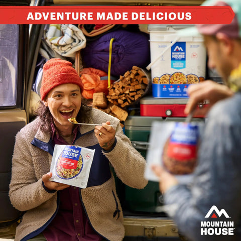 Person enjoying Fettuccine Alfredo With Chicken Freeze Dried Camping Meal For Outdoors Creamy Comfort Food by a packed car trunk.