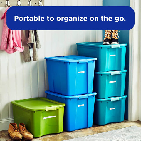 Stacked blue and green storage bins in a hallway, each with labeled fronts for easy organization.
