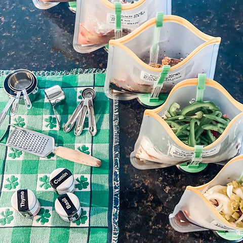 Upgrade Your Kitchen Grind With This Adjustable Ziplock Bag Holder Stand Featuring A Nonslip Base For Effortless Freezer Storage Hands Free Countertop Mount Keeps Plastic Bags Locked Down Straight Up In A Clean Green Set Of Four with filled bags and kitchen tools.