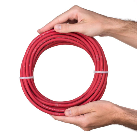 Man holding coiled Six Gauge Premium Extra Flexible Welding Cable 600 Volt Red 25 Feet Made In USA Sunlight Resistant Water Resistant