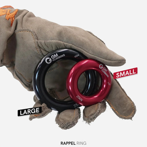 Gloved hand holding Black Large Rappel Ring 25kN for Rock Climbing Arborist Rescue Slackline Hammock Setup, side view