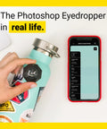 Portable Color Sensor And Color Matcher Tool With 300000 Plus Paint Library used on turquoise bottle next to smartphone.