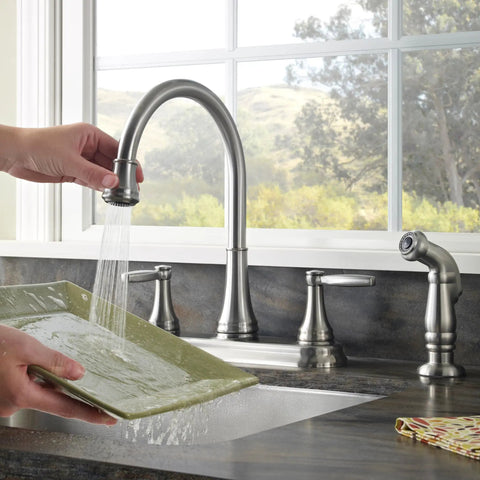 Glenfield 2-Handle High Arc Kitchen Faucet With Side Sprayer In Stainless Steel ADA Compliant Ceramic Disc Valve Tech Tri-Flow Water Control Built To Last No-Fuss Cleaning in use washing a dish beneath stream