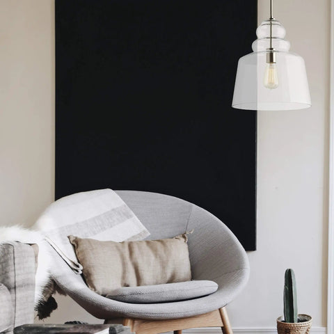 Agatha One Light Pendant In Brushed Nickel hanging over modern chair, highlighting sleek, contemporary design in home setting.