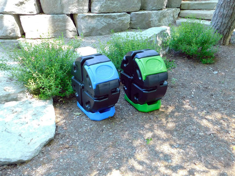 Two HotFrog Half Size Rolling Single Chamber Tumbling Composters in black and green, 19 gallon capacity, outdoors in a garden setting.