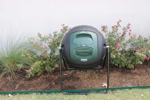 Front view of Ms Tumbles 35 Gallon Compost Tumbler with Easy Turn System, durable round design in black and green in a garden setting.