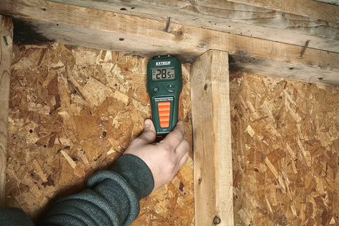 Hand using Pin And Pinless Moisture Meter For Wood And Building Materials, Noninvasive And Destructive Testing on wood wall