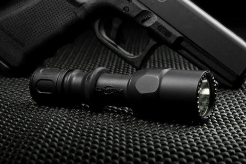 Beefy Dual Output LED Flashlight With Tailcap Click Switch 600 Lumens High For Maximum Brightness And 15 Lumens Low For Extended Runtime Tan Finish Great For EDC Outdoors And Tactical Use, shown on textured surface near a firearm