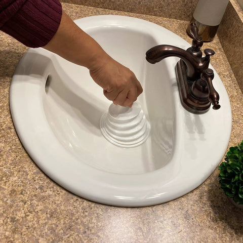 Mighty Tiny Plunger for Tight Bathroom and Kitchen Sinks, RV Ready, in action unclogging a compact white bathroom sink drain.