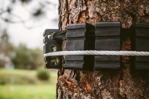 Close-up of Tree Saver Block Kit for Zip Line Dual Tree Setup with Adjustable Straps, 16 Heavy Duty Nylon Blocks on tree trunk