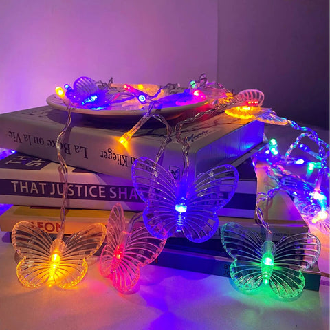 Butterfly Curtain String Lights With Remote USB Powered 48 LED Twinkle Lights 8 Modes Perfect For Bedroom Window Decor Party Wedding Holiday Christmas Multi Colored Glow Four Point Nine Feet displayed on books, showing multicolor glow.