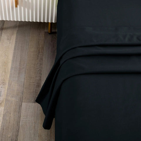Next Level Queen Flat Sheet In Sleek Black Delivers Top Tier Microfiber Comfort For An Insane Sleep Game With Wrinkle Free And Stain Resistant Features That Keep Your Bedding Looking Pristine Everyday, showing edges on a bed.