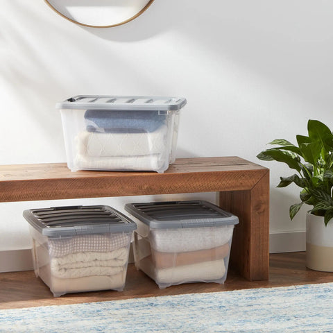 Straight Up Heavy Duty 32 Quart Clear Storage Bins With Secure Latching Lids stacked on a wooden shelf with blankets inside.