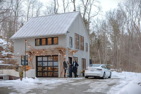 Modern house with a parked electric vehicle in winter, showing use of Go-To Portable Level 2 EV Charger With 40 Amp Output, 25ft Cable, 120V To 240V NEMA 14-50, Outdoor EVSE With LED Display, J1772 To Tesla NACS Adapter, Universal Charger For All US EVs.