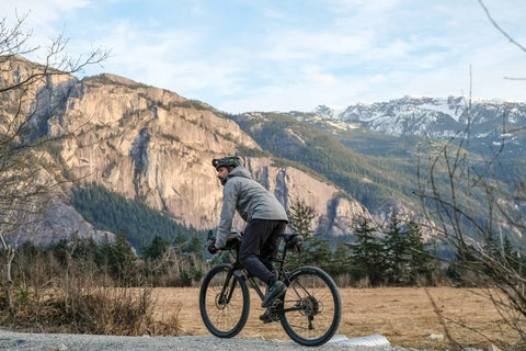Cyclist with Waterproof Under Saddle Seat Pack For Bike Commuting And Touring, Recycled Ripstop Bag Adjusts to Saddle, Mountain Background