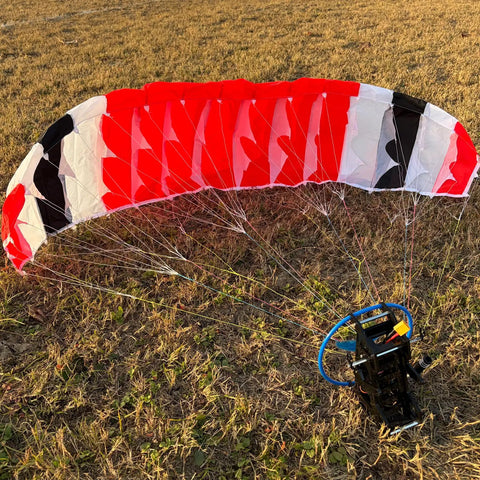 150cm Wingspan RC Paraglider PNP Kit With 2300KV 2205 Brushless Motor resting on grass with red, black, and white canopy.