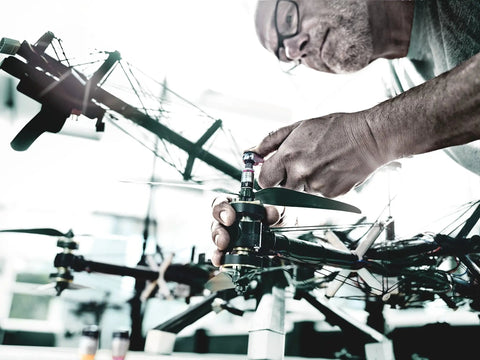 Person assembling a drone with careful precision, focusing on mechanical components and propeller installation in a workshop setting.