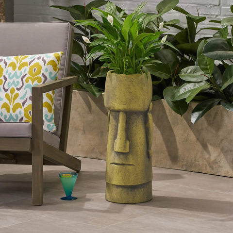 Outdoor Easter Island Tiki Urn Planter in Antique Green Finish on patio with plants, cast stone vase beside chair.