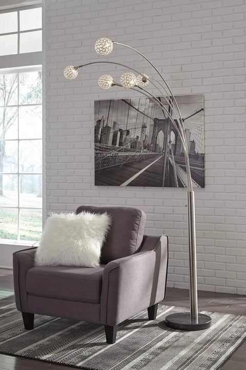 Modern floor lamp with crystal accents and arc design placed beside an armchair in a stylish living room setting.