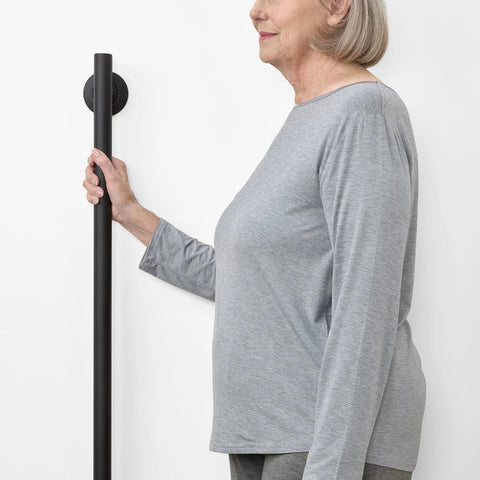 Woman gripping 24 Inch Straight Shower Grab Bar Matte Black Stainless Steel With Concealed Flanges for safety support.